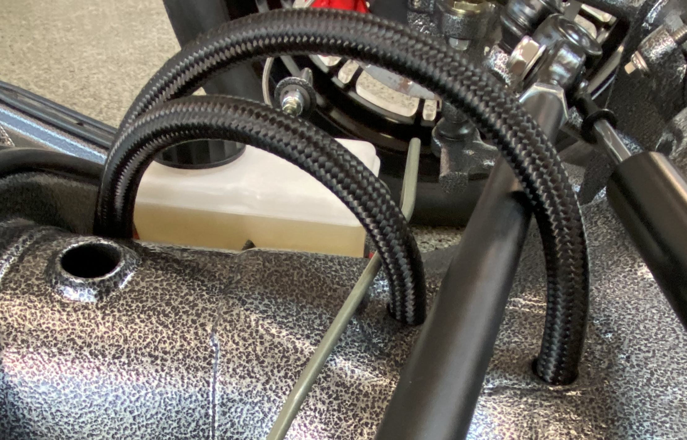 Close-up of the routed 6AN braided fuel line at the chassis exit